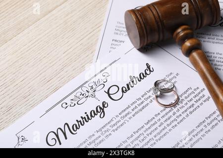 Contratto di matrimonio, fedi nuziali e martelletto su tavola di legno, primo piano Foto Stock