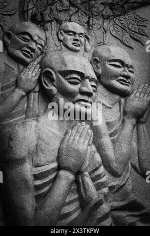 Un gruppo di monaci buddisti che pregano statue di fronte a un Buddha sdraiato a Nha trang Vietnam. Foto Stock