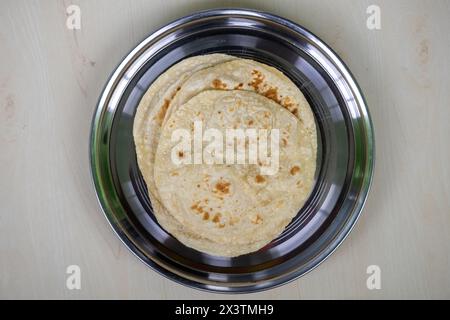Pane integrale o roti in un piatto d'acciaio su fondo di legno. Gustoso pasto bengalese (Bangladesh) che viene spesso mangiato con verdure o carne. Foto Stock