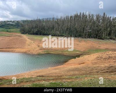 Montagne torreggianti, fiume con piccola isola visibile, cielo blu e bianco, riflessi visibili nell'acqua, il dono della natura del verde ovunque è la via. Foto Stock