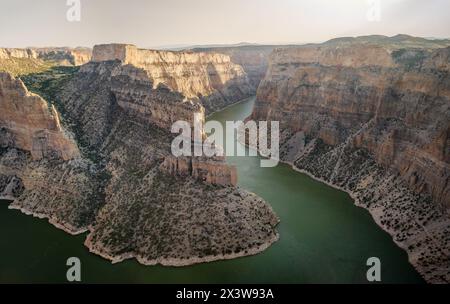 Una vasta veduta mostra un fiume che si snoda attraverso una gola a pareti ripide con scogliere stratificate pallide nell'area ricreativa nazionale di Bighorn Canyon. Foto Stock