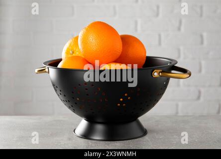 Arance fresche mature in colore nero su un tavolo grigio chiaro Foto Stock