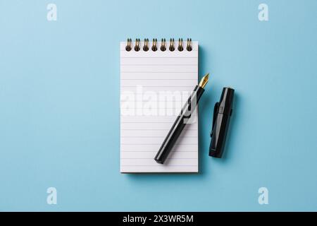 Vista dall'alto del notebook e della penna stilografica su sfondo blu Foto Stock