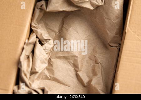 Scatola di cartone con riempitivo di carta marrone deformato pronta per l'imballaggio da vicino. Svuotare il contenitore di erogazione. Foto Stock