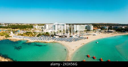 Ayia Napa, Cipro - 15 aprile 2023: Volo aereo sopra gli edifici di lusso di hotel con piscine sulla spiaggia con panorama della vegetazione dell'isola. La sabbia bianca più famosa Foto Stock