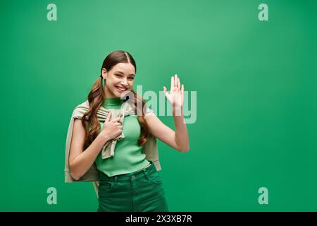 Una giovane donna di 20 anni indossa una camicia verde e pantaloni coordinati in un ambiente da studio, trasudando eleganza e stile senza tempo. Foto Stock