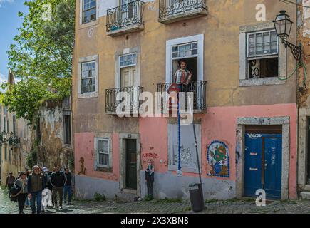 LISBONA, PORTOGALLO - 8 APRILE 2024: Divertente cantante di strada che esegue arie d'opera dal balcone della sua casa situata in una strada nella pittoresca Foto Stock