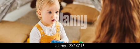 Una giovane madre si impegna felicemente con la figlia, giocando insieme in una stanza accogliente Foto Stock