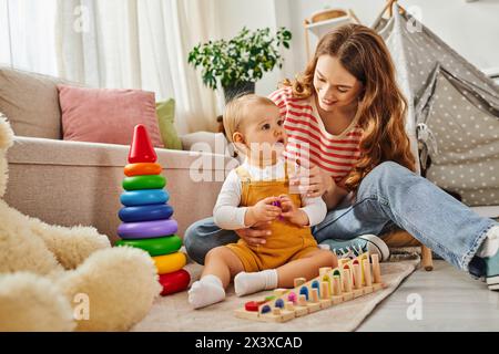 Una giovane madre si impegna con gioia con la figlia, interagendo giocosamente in un ambiente caldo e accogliente. Foto Stock