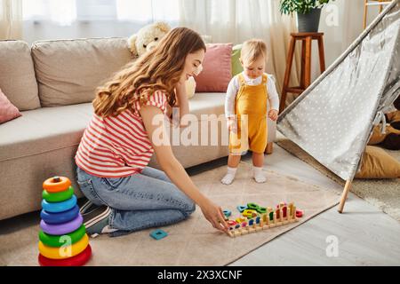 Una giovane madre interagisce felicemente con la figlia mentre gioca sul pavimento a casa. Foto Stock