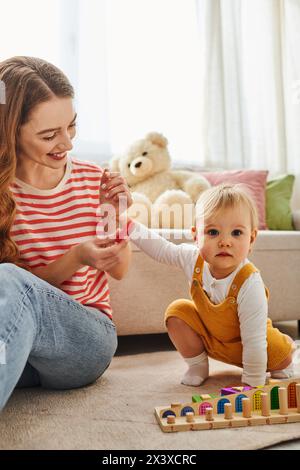 Una giovane madre interagisce gioiosamente con la figlia mentre gioca insieme sul pavimento di casa. Foto Stock