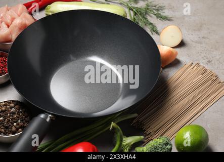 Wok del ferro vuoto e ingredienti crudi su un tavolo grigio Foto Stock