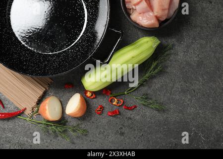 Wok del ferro vuoto e ingredienti crudi su un tavolo grigio, in posizione piatta Foto Stock