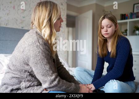 Madre matura seduto sul letto con infelice figlia adolescente a casa discutere di problemi Foto Stock