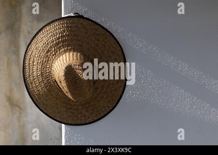 cappello di paglia appeso alla parete, luce naturale soffusa del tramonto Foto Stock