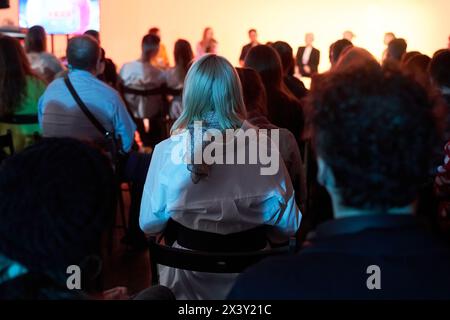 Sfondo di persone irriconoscibili in piedi con la schiena verso la telecamera e di fronte al palco in cui gli altoparlanti stanno parlando. Evento aziendale. Foto di alta qualità Foto Stock