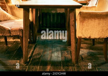 Primo piano di sedie in velluto giallo attorno a un tavolo di legno in un bar in stile grunge con spazio per copiare. Foto di alta qualità Foto Stock