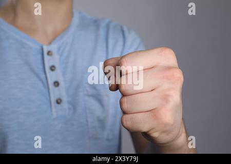 Uomo che mostra pugno con spazio per tatuaggi su sfondo grigio, messa a fuoco selettiva Foto Stock