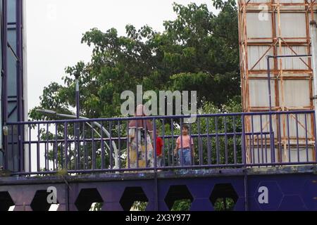 Una madre che ha portato i suoi due figli a camminare sul ponte pedonale Foto Stock