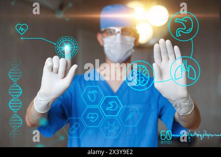 Display tattile uniforme Doctor in Blue con infografiche. Chirurgo professionista moderno in sala operatoria. Icone mediche sul desktop. Foto Stock