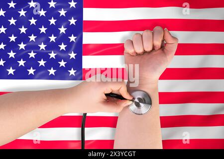 La testa di uno stetoscopio medico sul polso (primo piano) sullo sfondo della bandiera degli Stati Uniti. Concetto di sistema sanitario STATUNITENSE Foto Stock