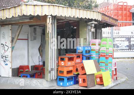 Pile di casse vuote per bottiglie e pile di sedie di plastica corte in un vecchio negozio sul lato della strada Foto Stock