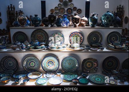 Piatti e vasi in ceramica uzbeka fatti a mano con tradizionali motivi asiatici dipinti a mano sugli scaffali del negozio di stoviglie orientali Foto Stock