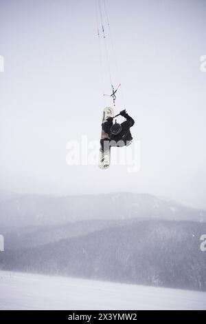 Un uomo medio-adulto ottiene grande aria mentre fa il kiting sulla neve in Alaska. Foto Stock