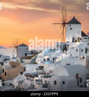 Ora d'oro sopra gli iconici mulini a vento di Oia arroccati sulle scogliere della Caldera Foto Stock