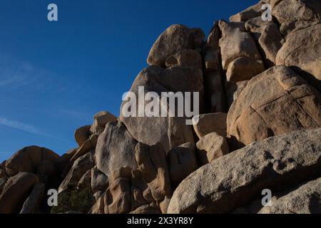 Giganti di granito illuminati dal sole si ergono alti sotto il cielo di Joshua Tree Foto Stock