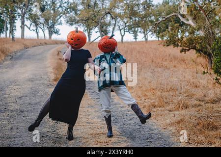 Due amiche che indossano teste di zucca intagliate Foto Stock