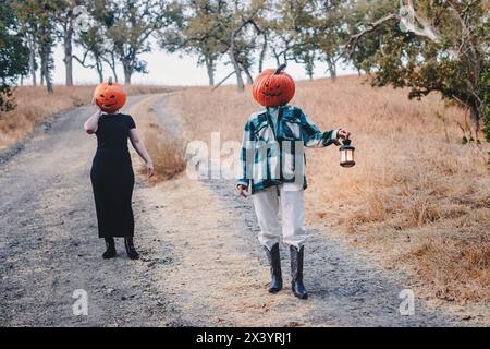 Due amici che indossano teste di zucca di Halloween intagliate Foto Stock