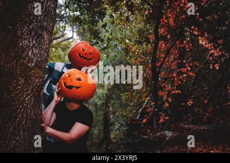 Due amici che indossano teste di zucca scolpite di Halloween con volti spaventosi Foto Stock