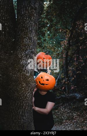 Due amici che indossano teste di zucca scolpite di Halloween con volti spaventosi Foto Stock