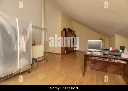 Grande ufficio in una sala attico con grandi finestre con lucernari, radiatori in alluminio bianco e pavimenti in parquet di quercia Foto Stock