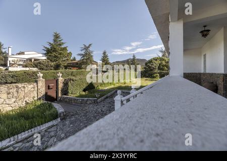 Vista sui giardini di una casa con balaustre bianche da una lunga terrazza esterna Foto Stock