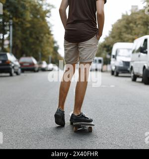 Uomo che cavalca su Uno skateboard. Gambe su Uno skateboard. Foto Stock