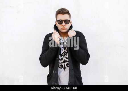 Young Handsome Man con occhiali da sole e Un pullover su sfondo bianco. Foto Stock