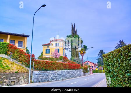 Le scenografiche case residenziali con giardini lussureggianti lungo la strada in Collina d'Oro, Svizzera Foto Stock