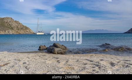 Barca a vela in acque tranquille al largo della costa di Mykonos; Mykonos, Egeo meridionale, Grecia Foto Stock