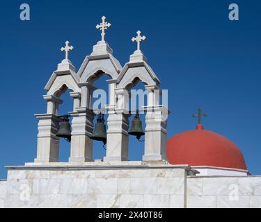 Dettagli architettonici di campane e croci e una cupola rossa sul Monastero di Panagia Tourliani contro un cielo blu brillante a Mykonos, in Grecia Foto Stock