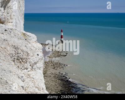 Faro di Beachy Head visto dal percorso costiero sopra, con bianche scogliere di gesso e una barca a vela in lontananza, East Sussex, Regno Unito Foto Stock
