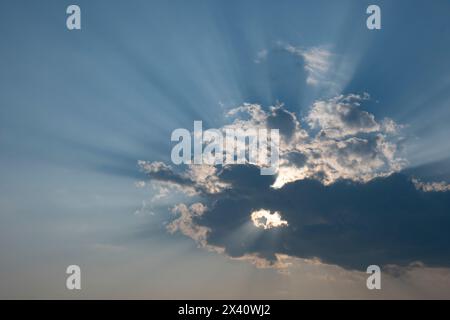 La luce del sole scorre da una formazione di nuvole scure e illumina un cielo blu; Lake of the Woods, Ontario, Canada Foto Stock