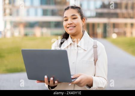 Ragazza con camicia bianca che tiene un laptop all'aperto Foto Stock