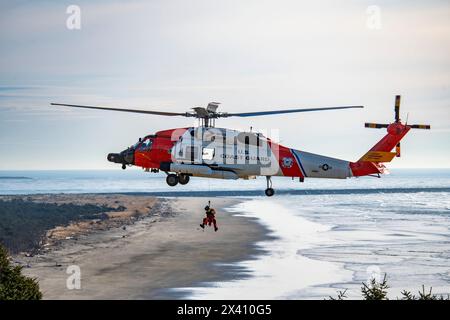 Equipaggio della Guardia Costiera degli Stati Uniti sospeso sotto un Sikorsky MH-60J Jayhawk che svolge esercitazioni di soccorso al Cape Disappointment State Park vicino al Mo... Foto Stock