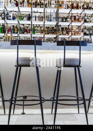 Sgabelli da bar e bottiglie di alcol in mostra dietro il bar; Grecia Foto Stock