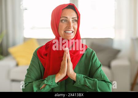 Donna che indossa l'Hijab rosso e verde, che prega Foto Stock