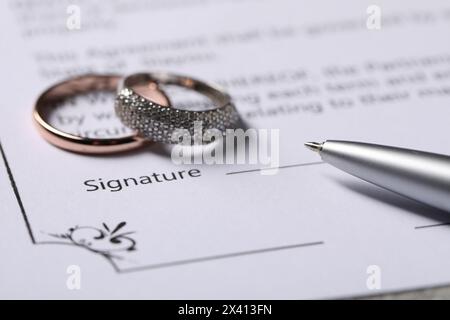 Contratto di matrimonio, penna e fedi nuziali, primo piano Foto Stock