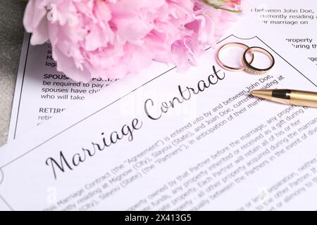 Contratto di matrimonio, fedi nuziali, penna e fiori sul tavolo, primo piano Foto Stock