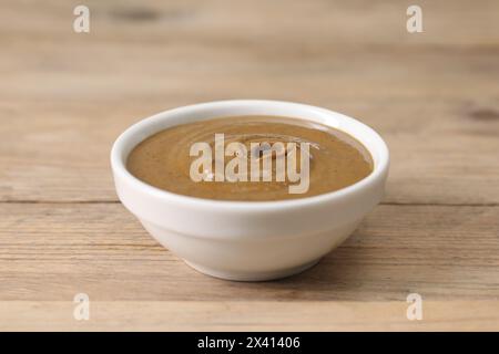 Delizioso burro di noci nel recipiente su un tavolo di legno, primo piano Foto Stock